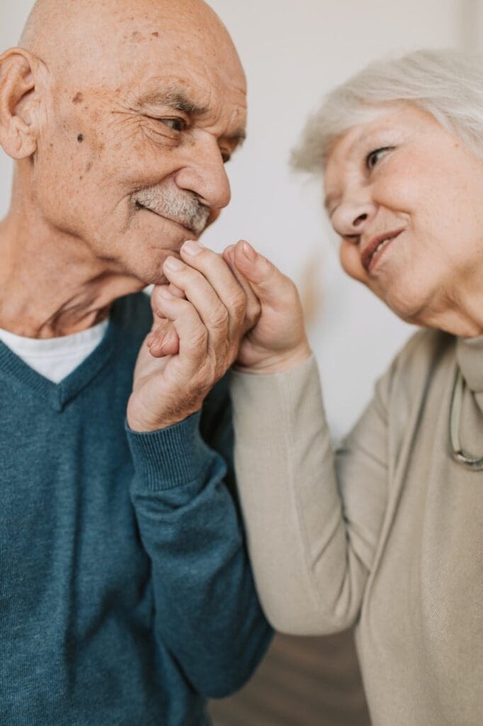 Two senior residents smiling and holding hands