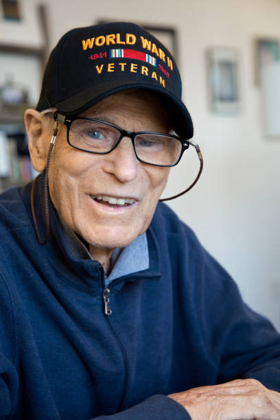 An elderly veteran smiling, wearing a cap.