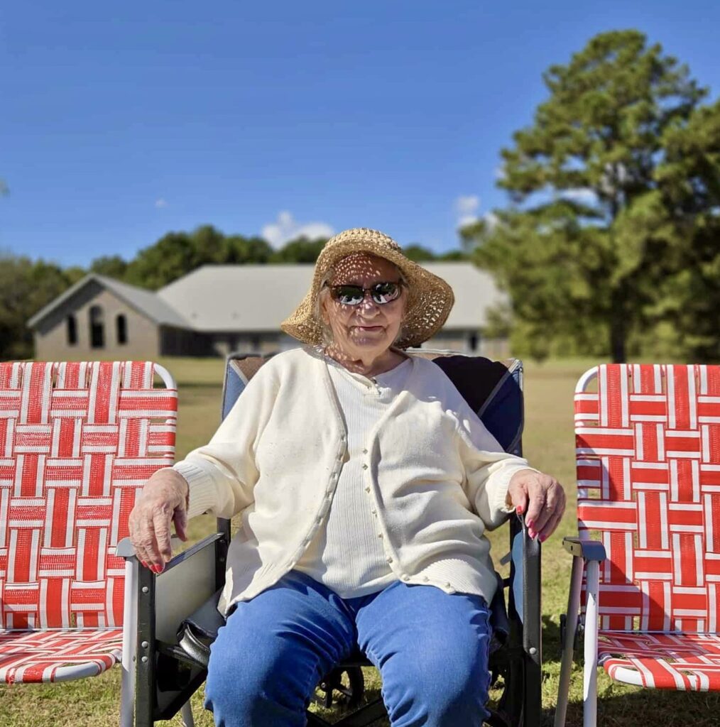 A woman sitting outdoors in a chair with a sun hat