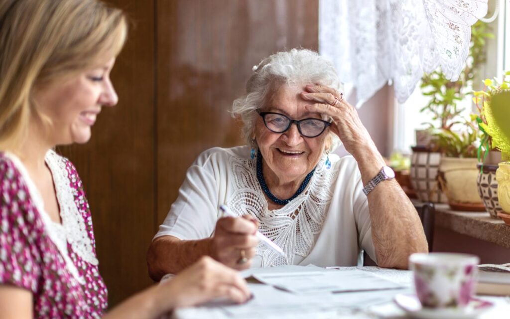 An elderly woman happily engaging with a caregiver at a table