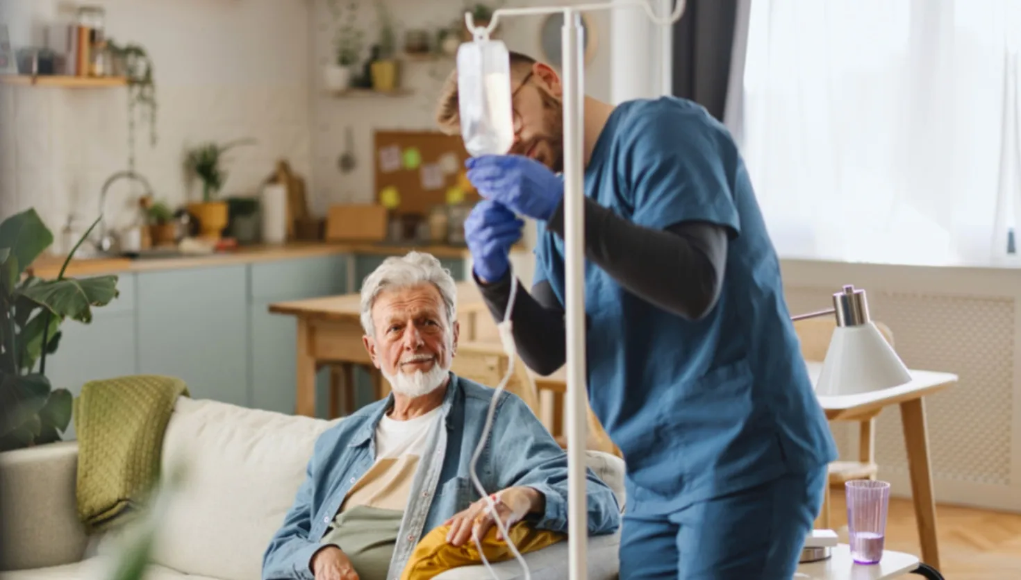 Healthcare worker assisting senior patient in a living room.