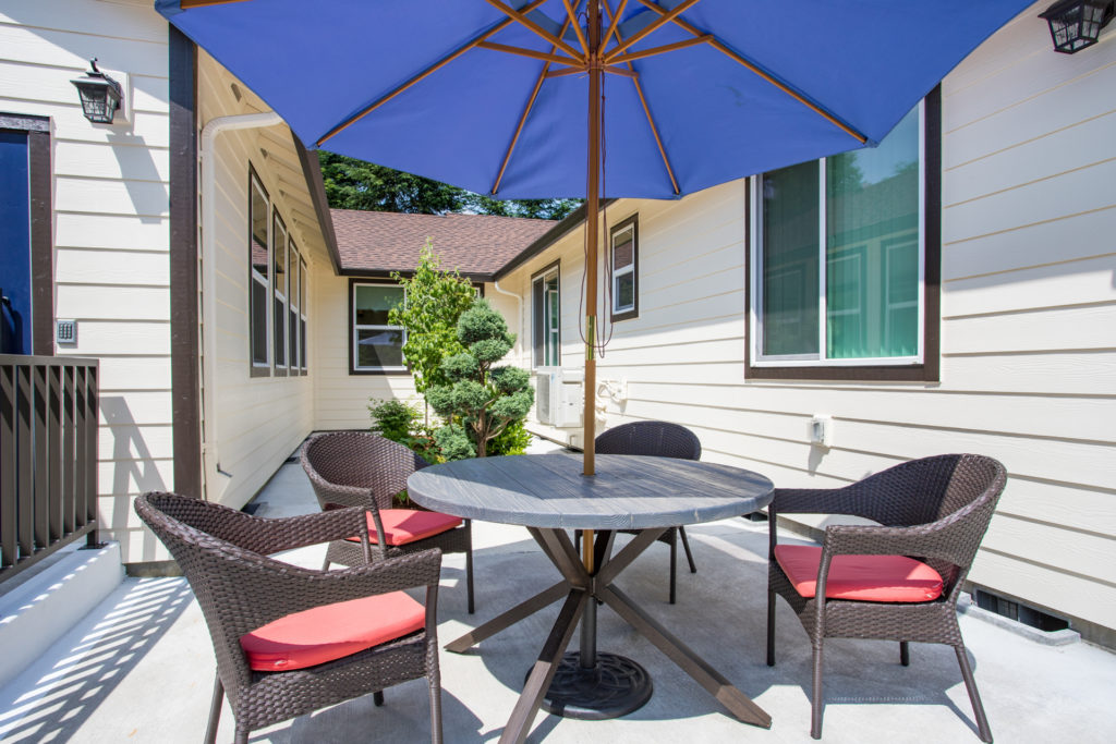Patio area with a table and chairs under an umbrella.