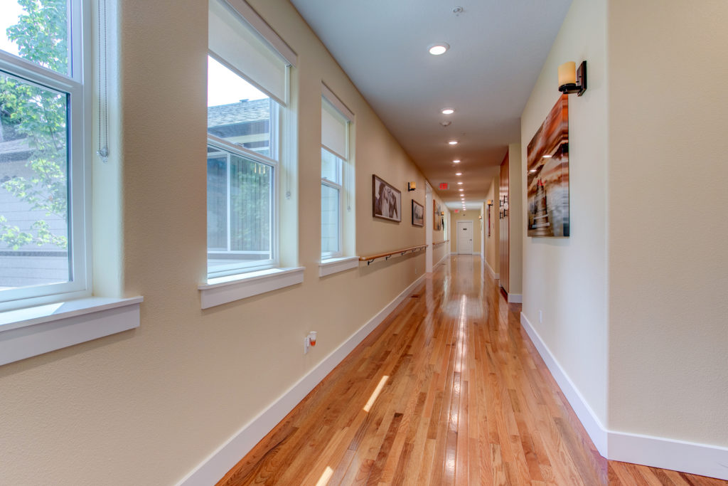 Well-lit hallway with artwork and wooden flooring