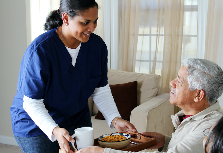 Staff serving food to a resident in a warm setting.