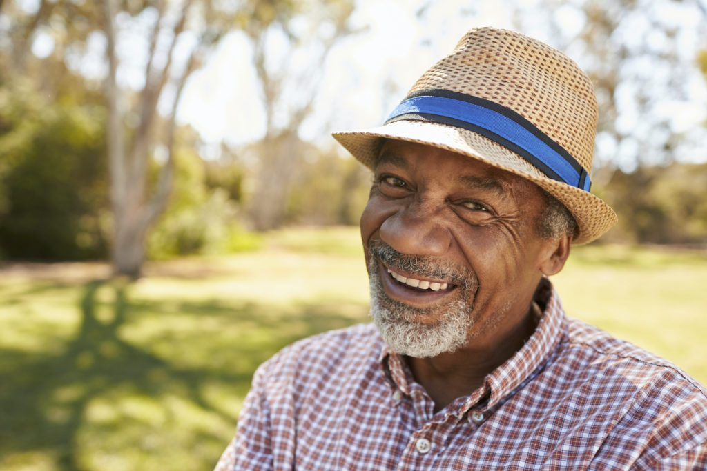 Smiling senior man in a straw hat outdoors.