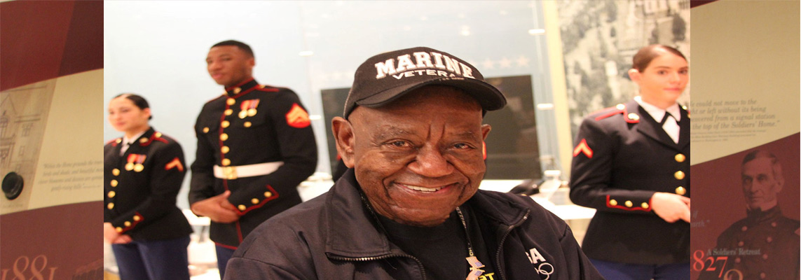Smiling veteran in a formal setting with other service members.