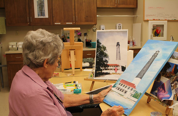 Resident painting at an arts and crafts table.
