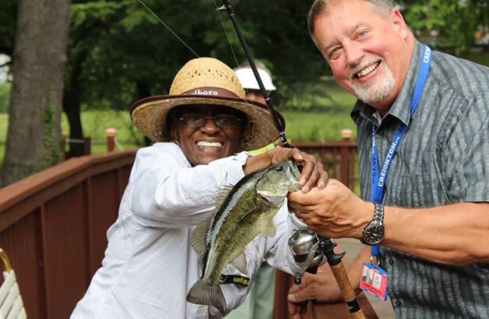 Two men smiling while fishing outdoors.