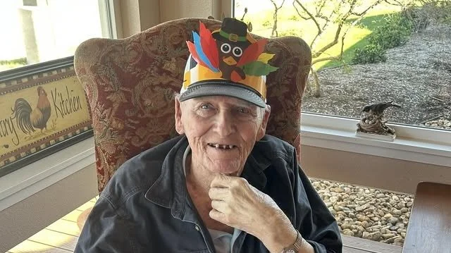 Senior resident wearing a festive hat in a sunny common area