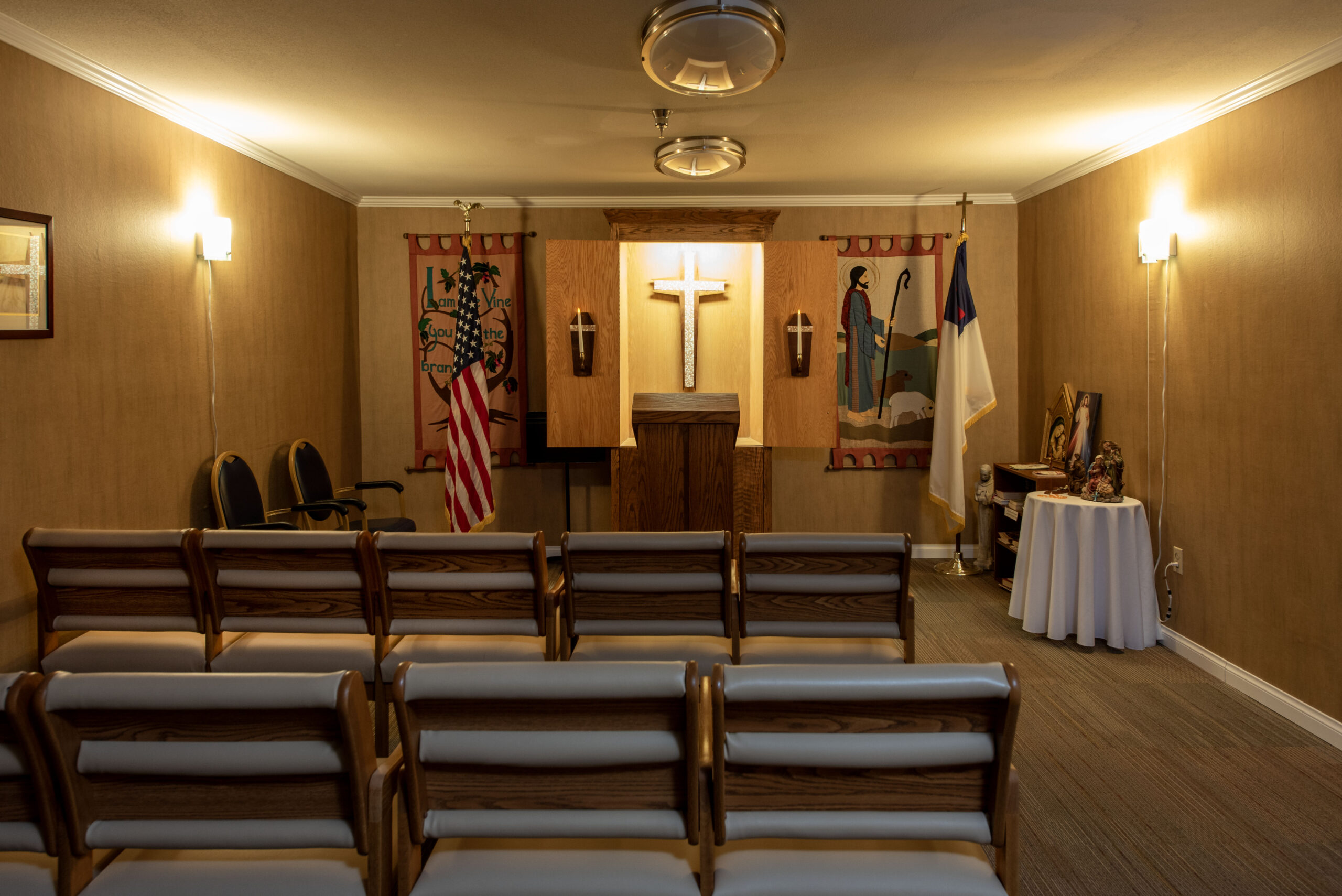 Chapel interior with seating, cross, and flags