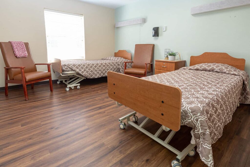 A shared resident room with two beds and chairs