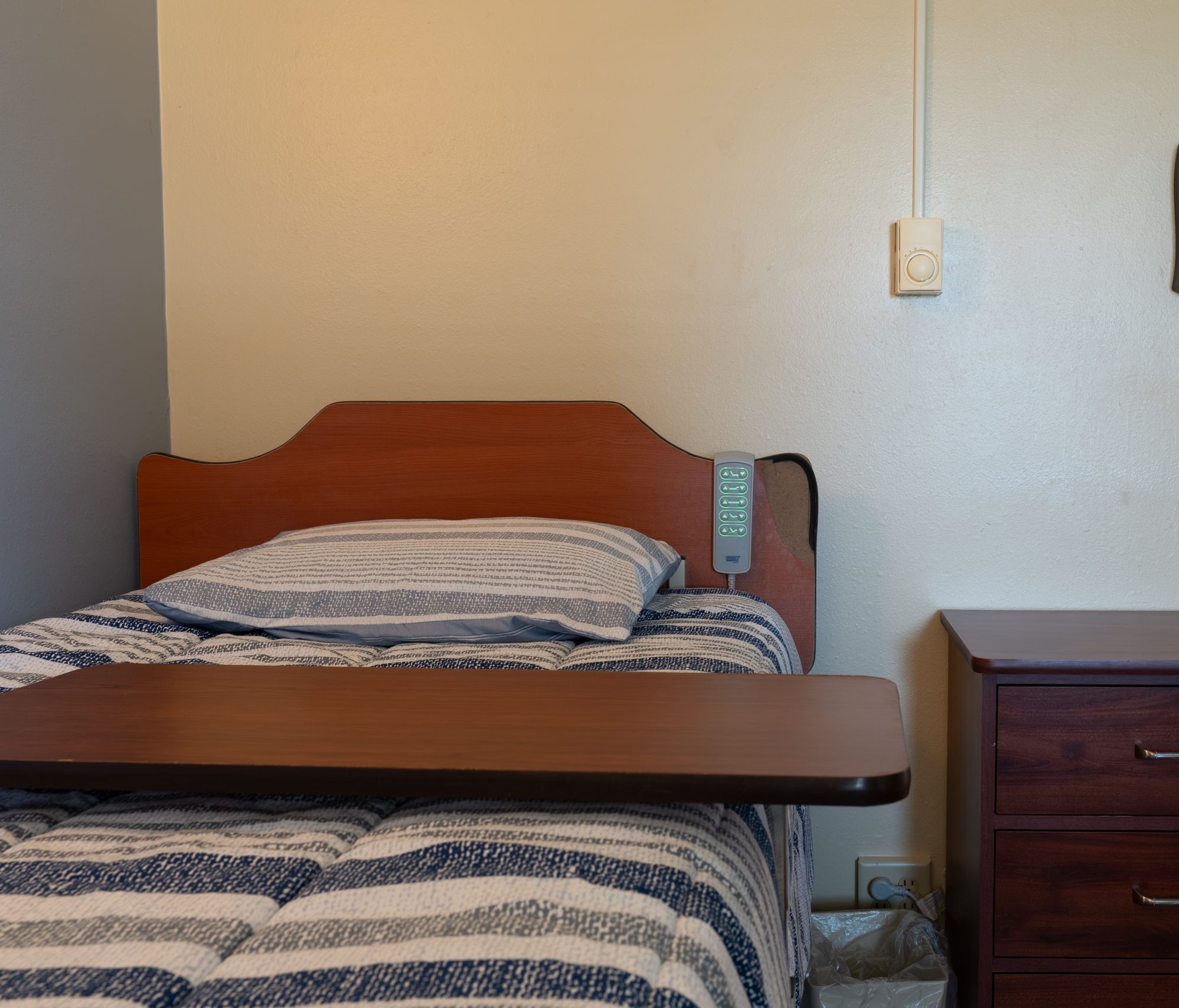 A private resident room with a bed and nightstand