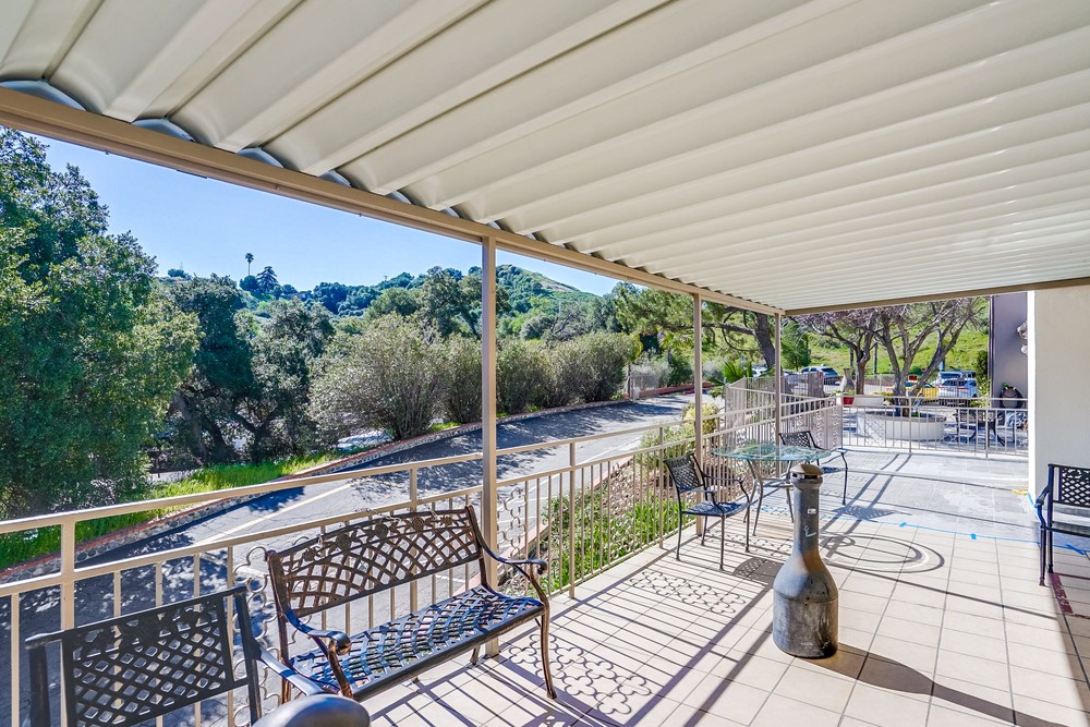 Covered patio area with seating and greenery