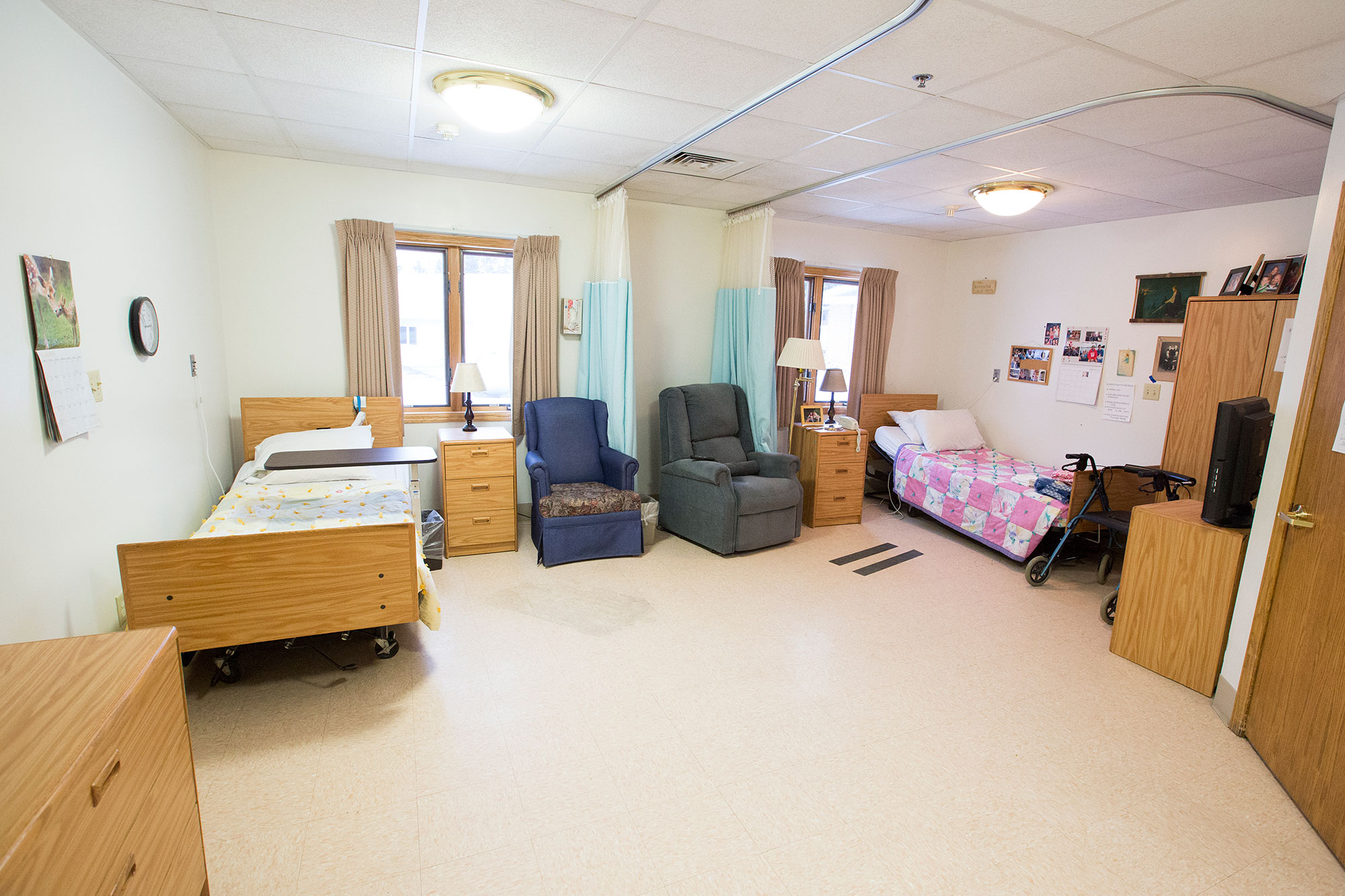 A bright resident room with two beds and seating areas