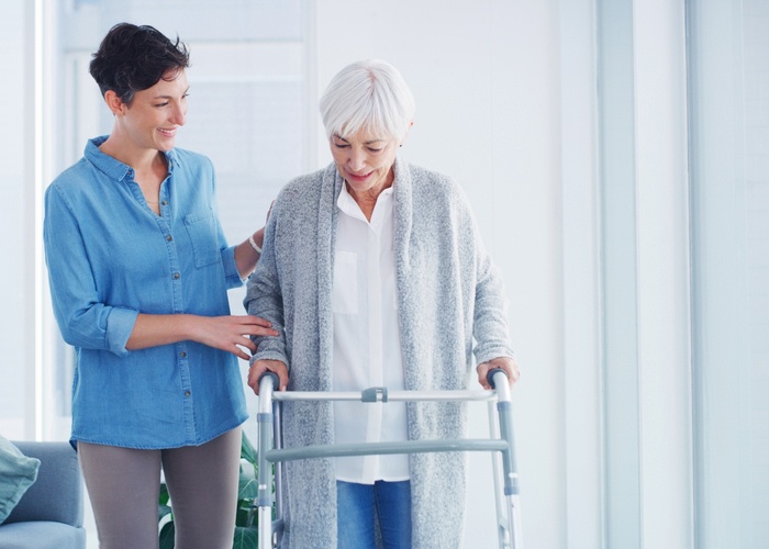 Caregiver assisting senior woman with walker