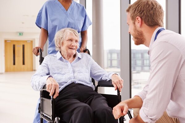 Staff assisting a smiling resident in a wheelchair