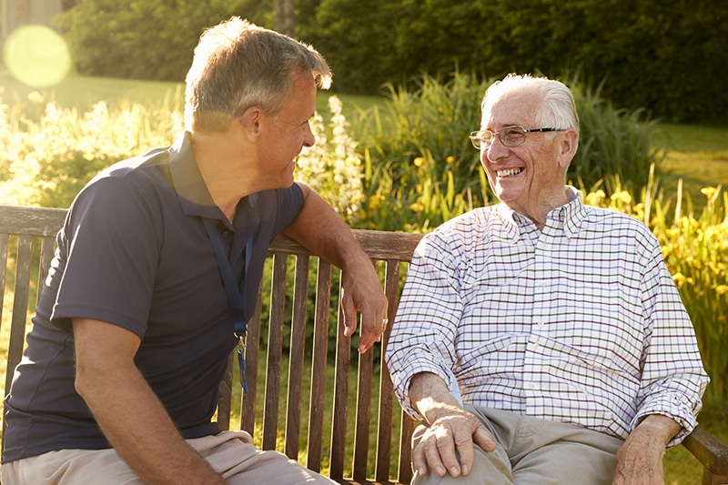 Resident laughing with staff in a garden