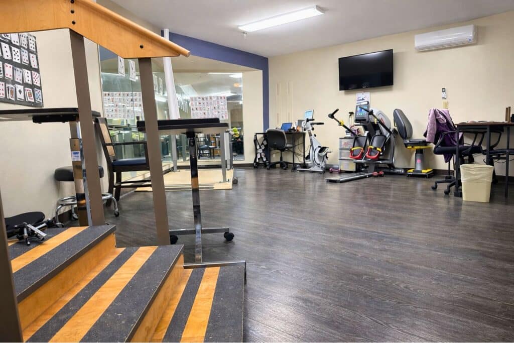 Interior of a fitness area with equipment and stairs.