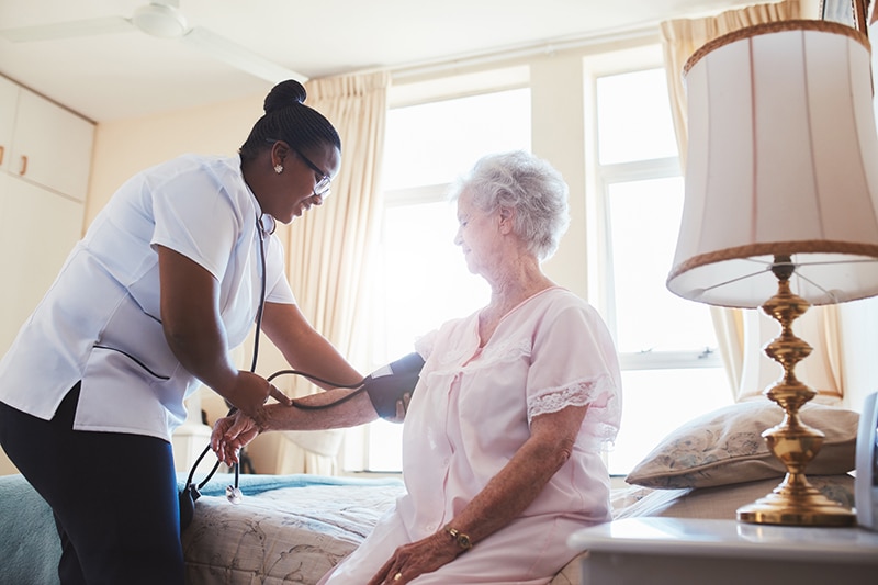 Caregiver taking a resident's blood pressure in a room