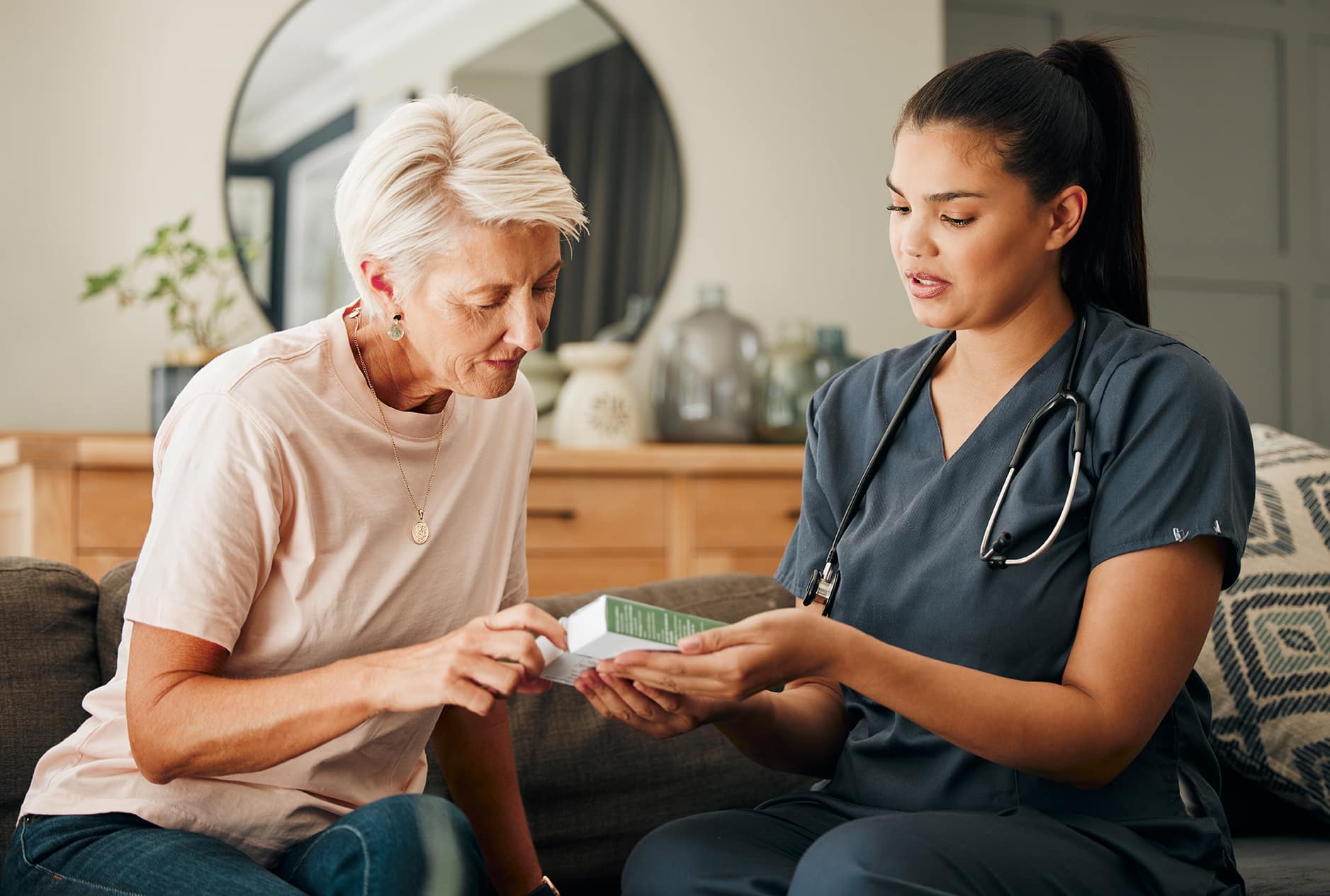 Female caregiver assisting senior woman with a product