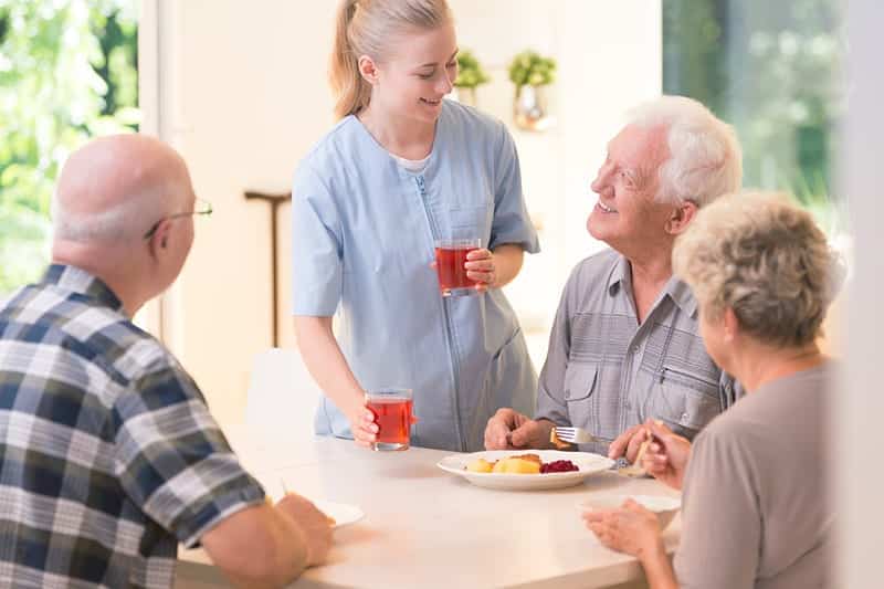 Residents enjoying a meal with staff assistance
