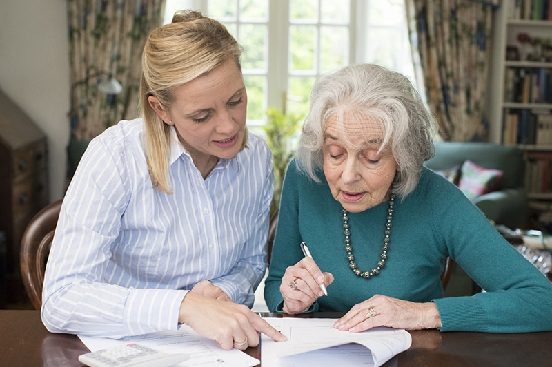 Caregiver assisting an elderly resident with paperwork.