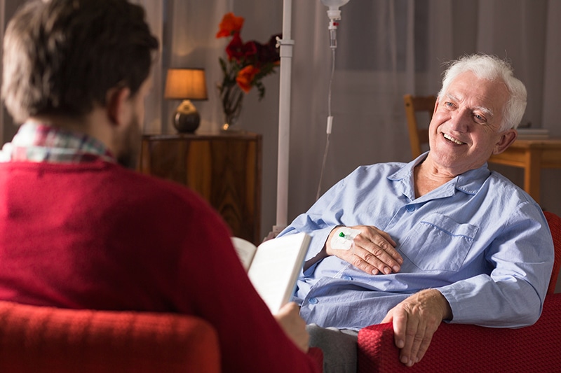 Elderly man smiling and engaging with a caregiver.