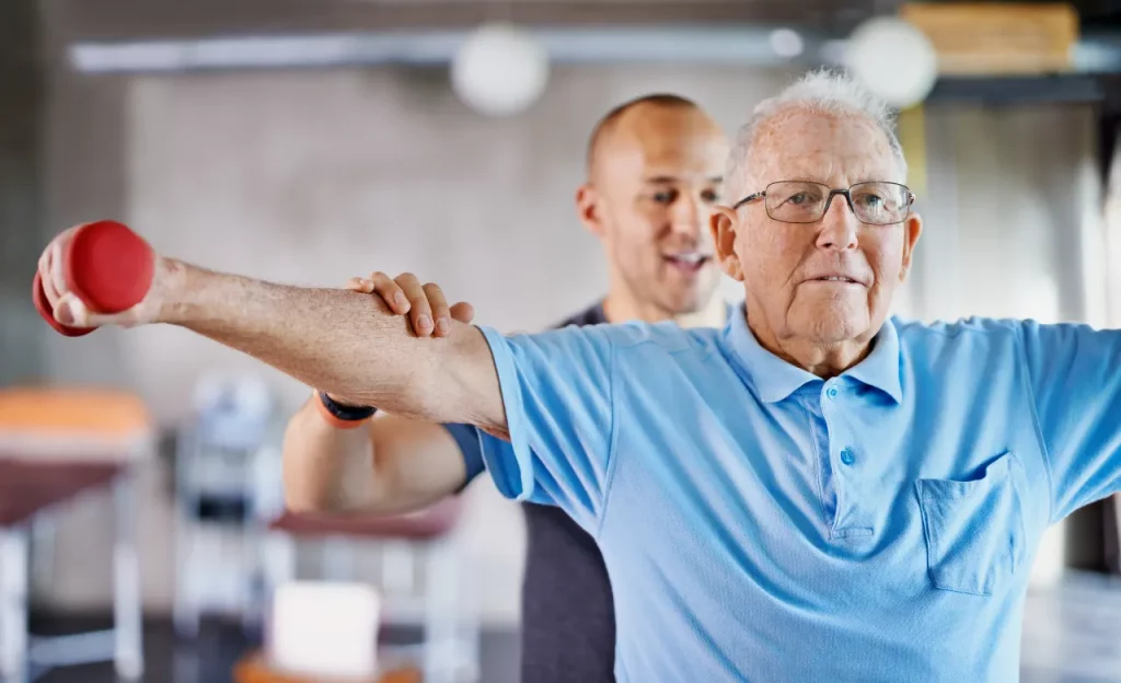 Senior man doing physical therapy with trainer.