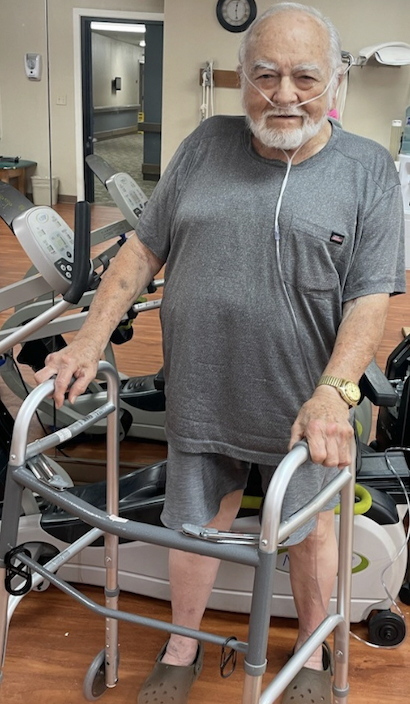 Senior man using walker in therapy area.