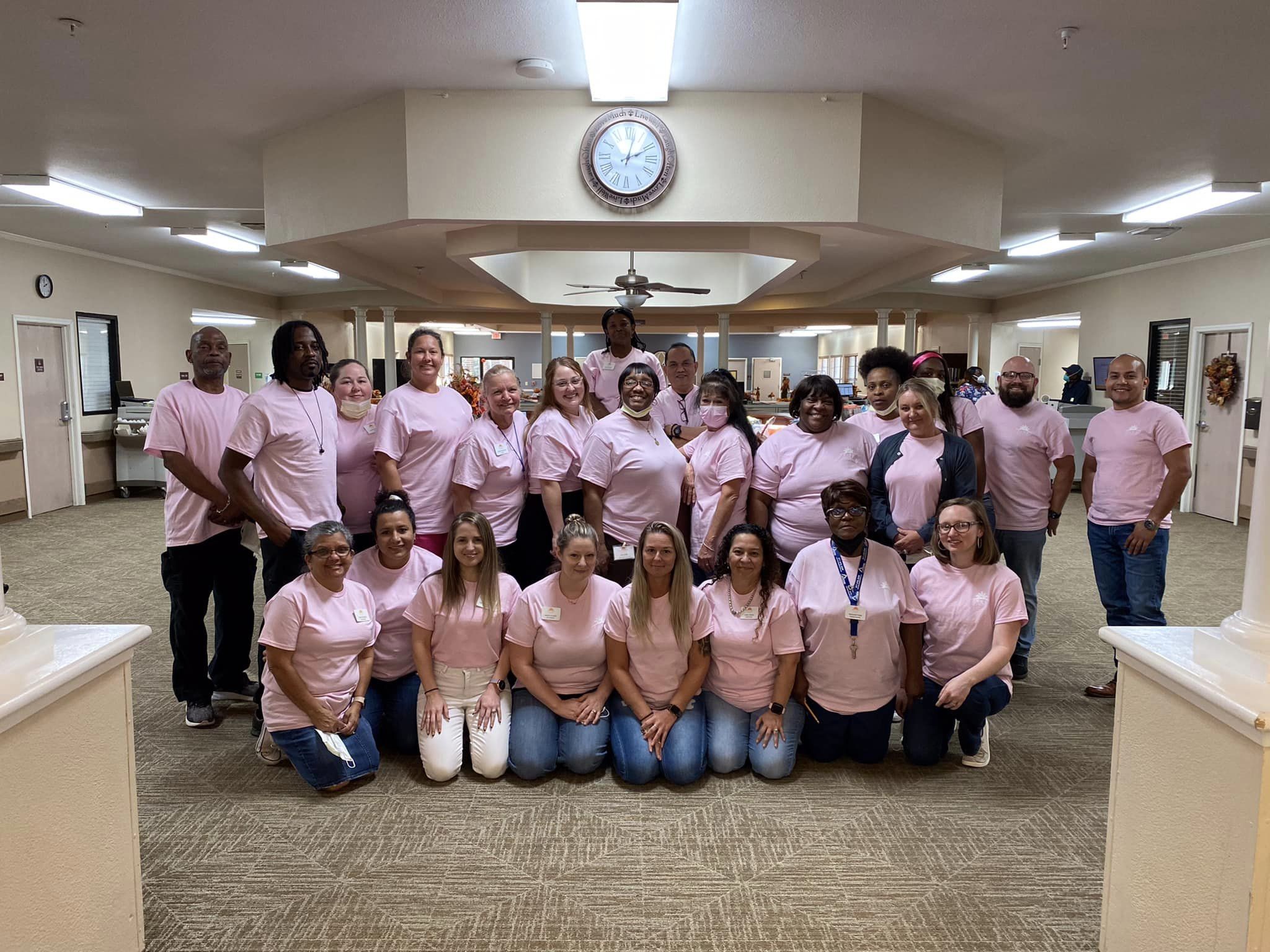 Staff members posing together in pink shirts
