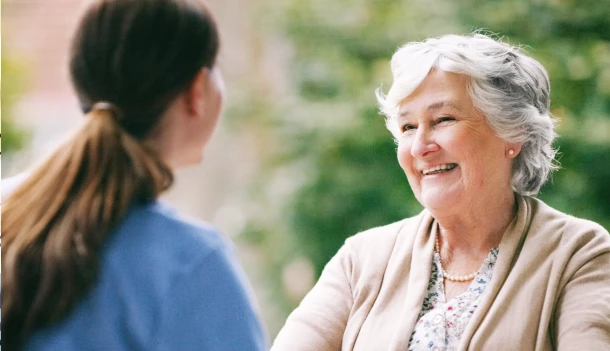 Resident engaging with staff outdoors, smiling.