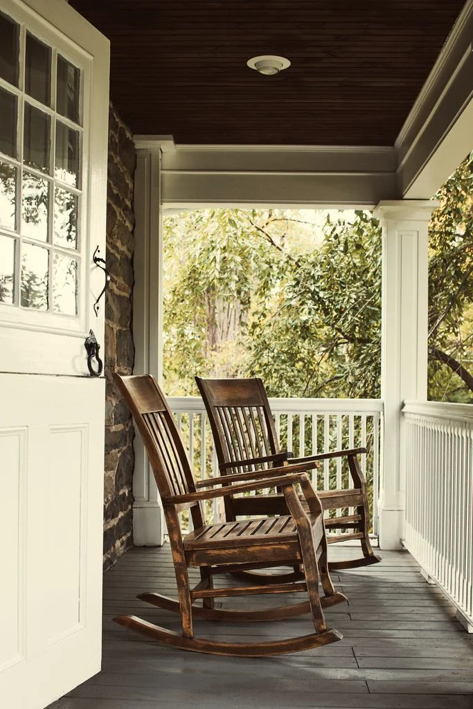 Two wooden rocking chairs on a porch
