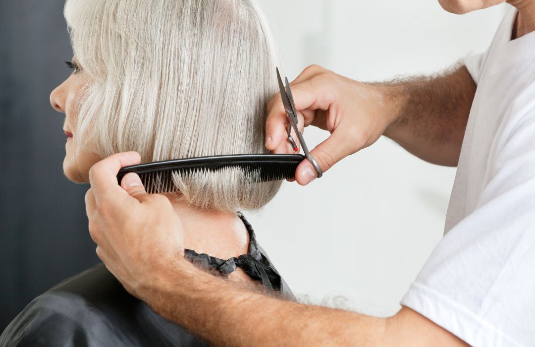 A stylist cutting the hair of a senior woman