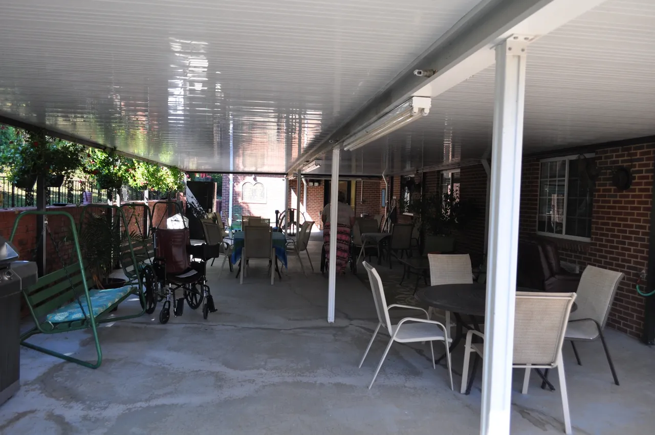 Covered outdoor area with seating and nearby greenery
