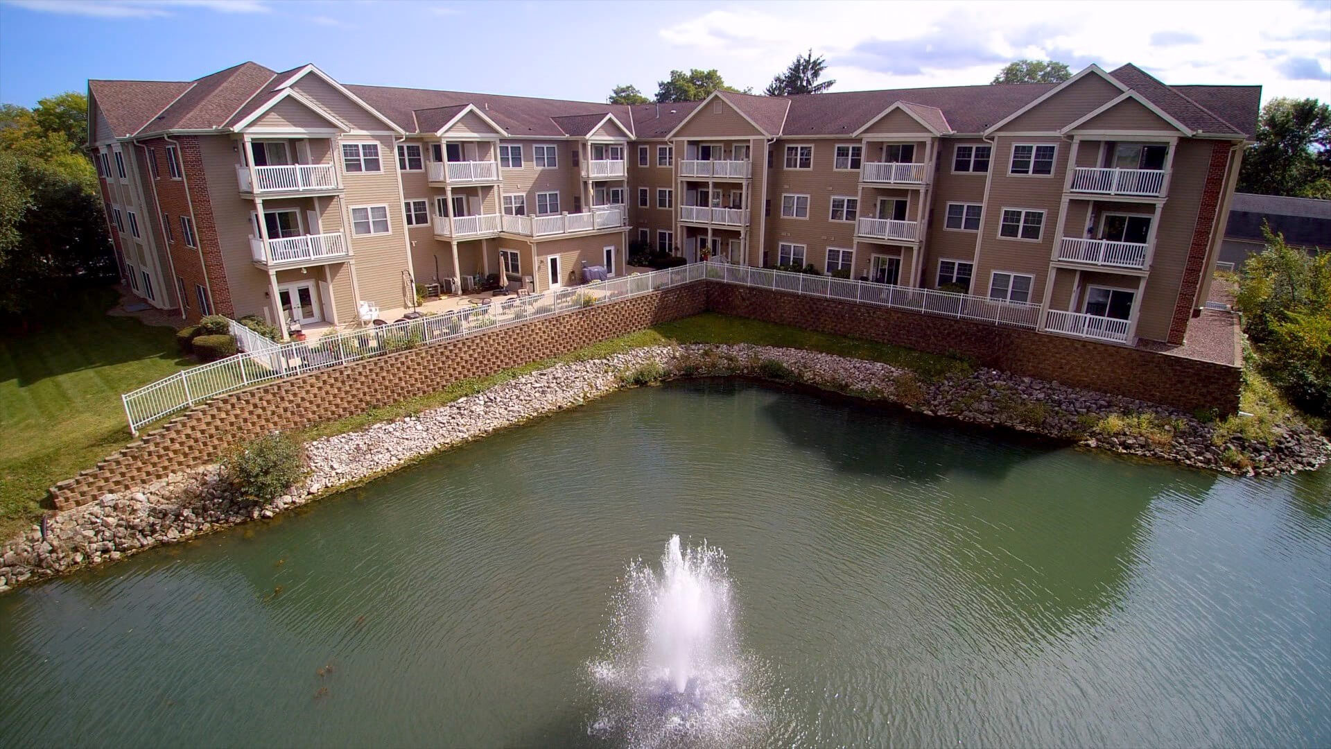 Exterior view of Willowbrook Place with a pond and fountain