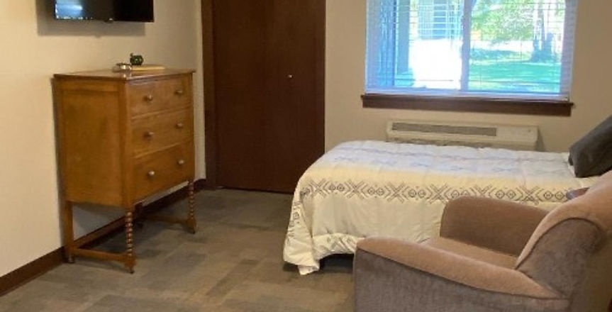 A cozy resident room with a bed and chair