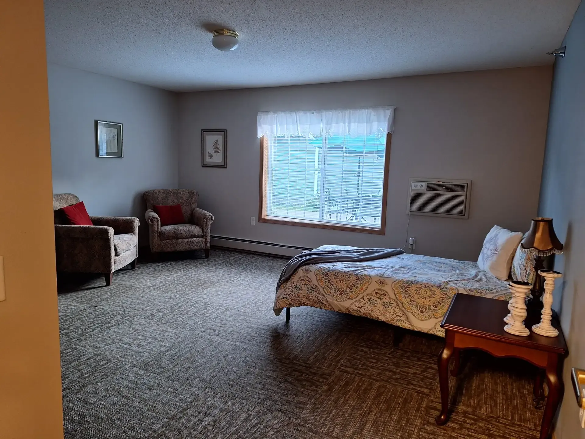 A well-furnished private resident room with a bed and seating area
