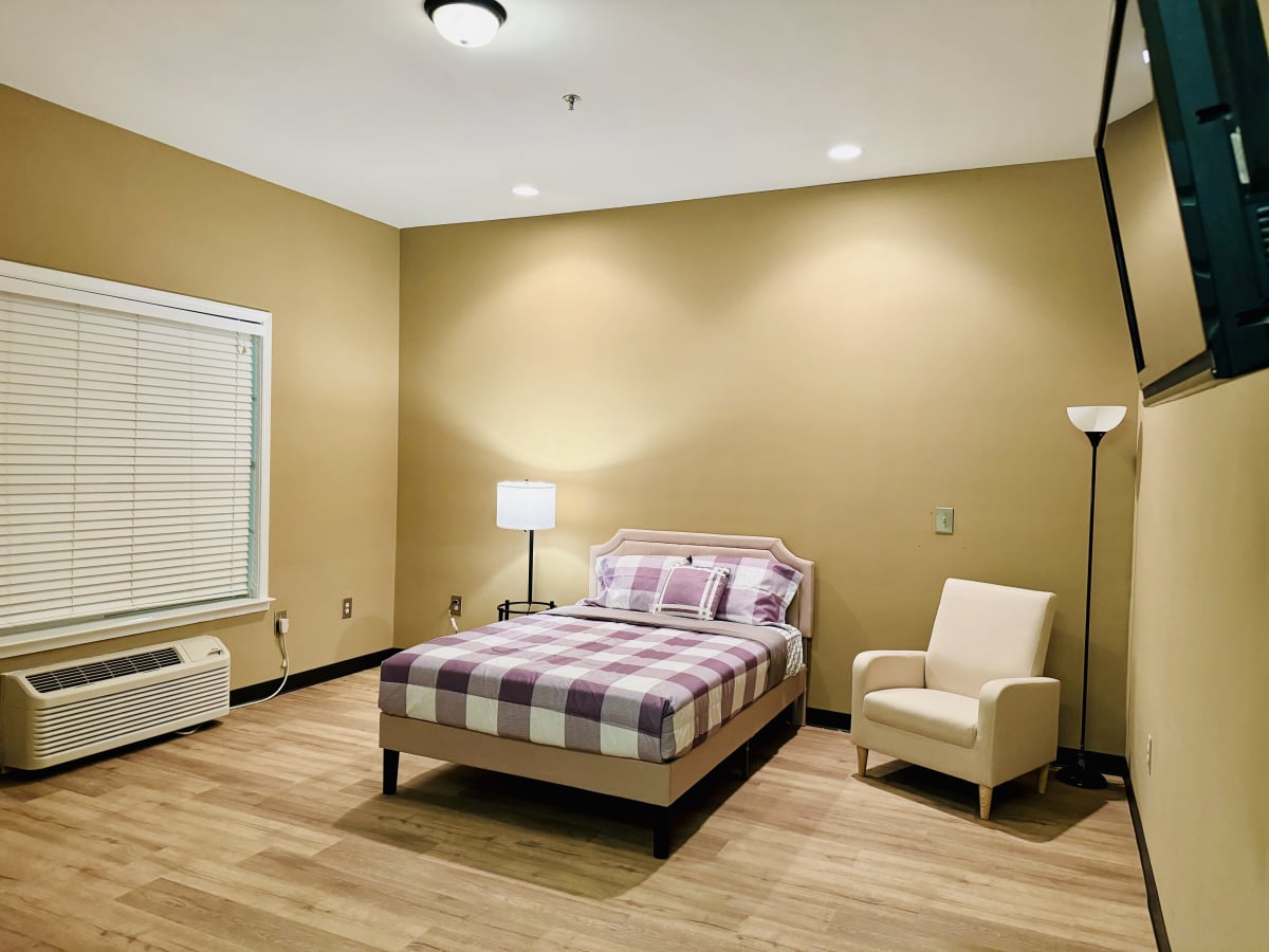 Bright resident room with bed and chair