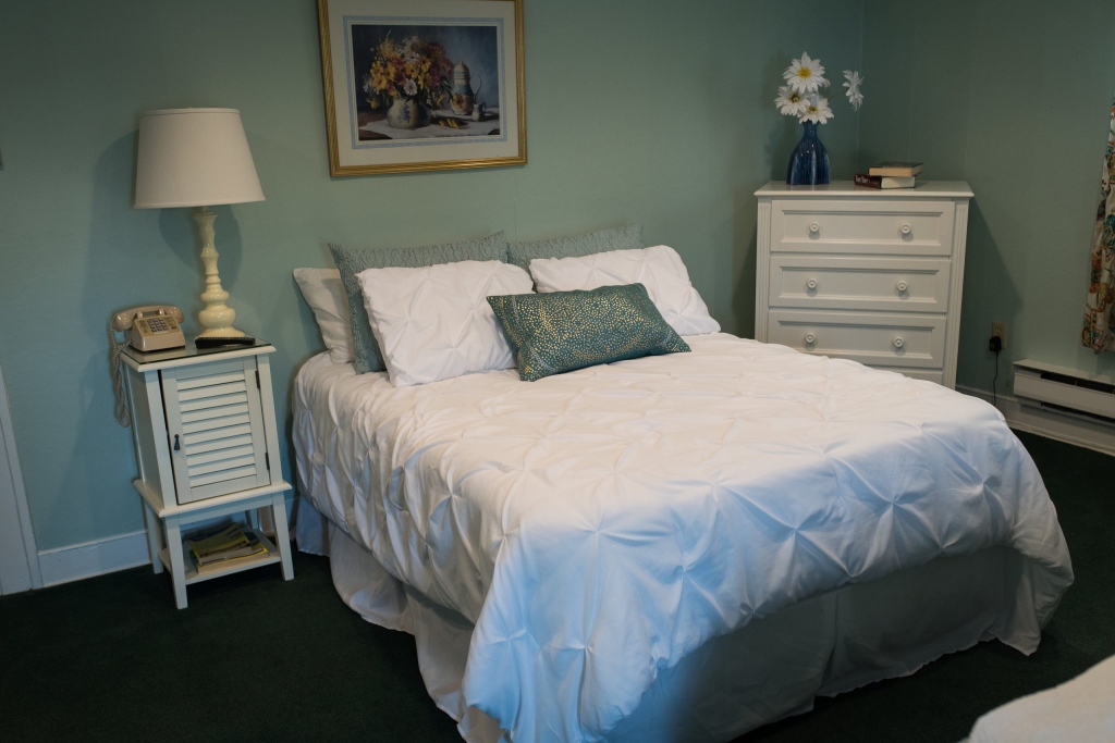 Cozy bedroom setup with bed, lamp, and dresser