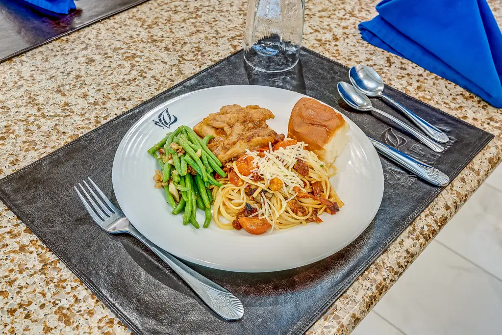 A plated meal with green beans, chicken, and spaghetti