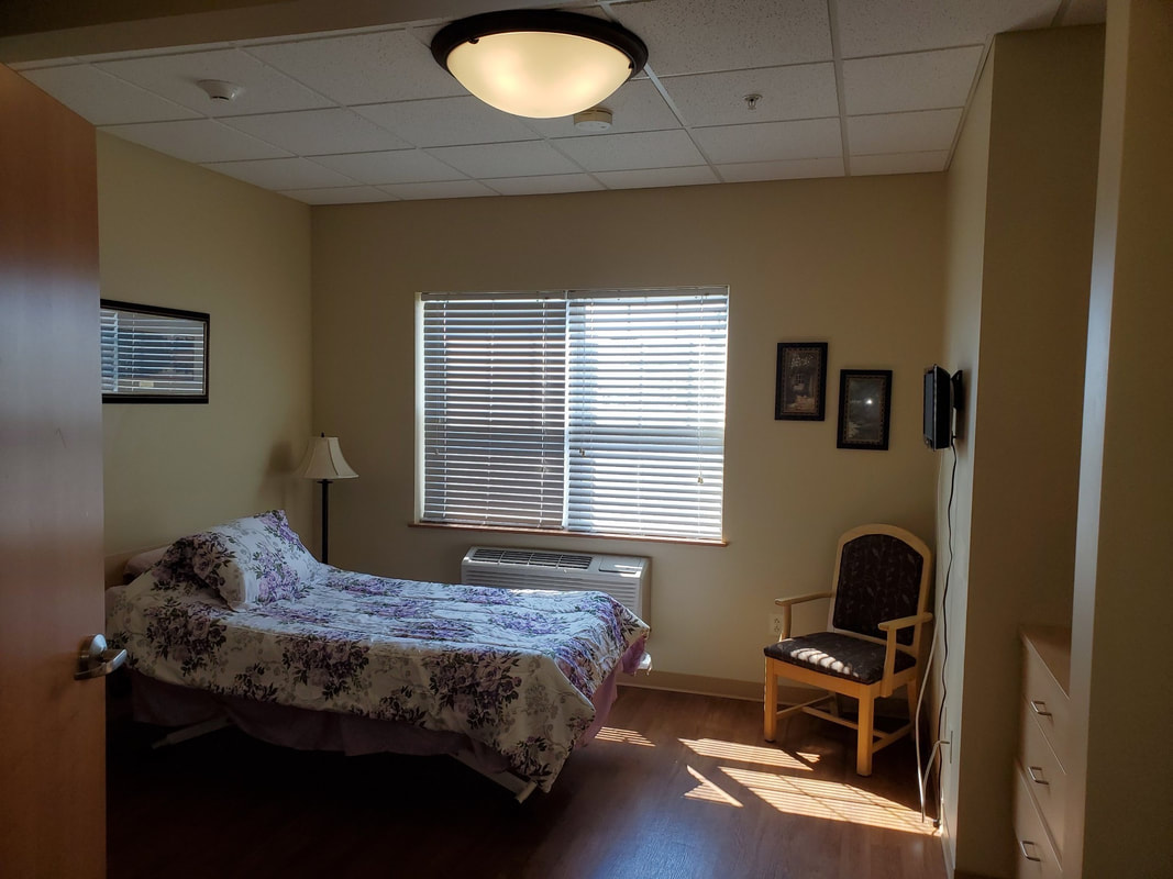 Cozy private room with a bed and chair in sunlight