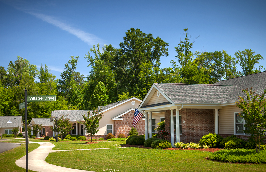 Residential buildings along Village Drive with a blue sky