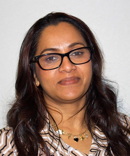 A woman with glasses smiling at the camera