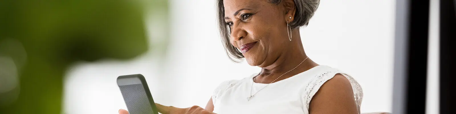 Senior woman engaged with a device indoors