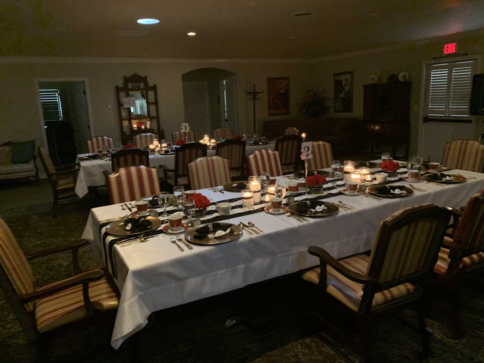 A dining room set for a meal with candles and flowers.