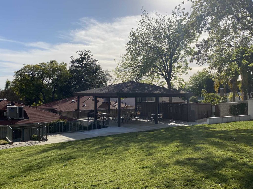 Outdoor patio area with shade structure and greenery.