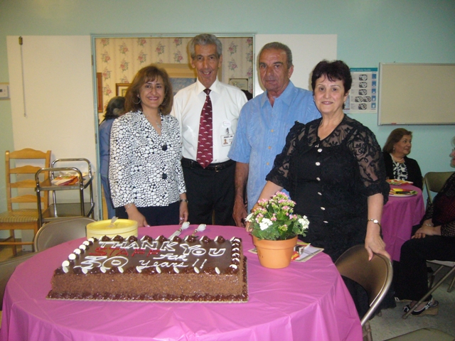 Celebration with residents and staff around a cake.