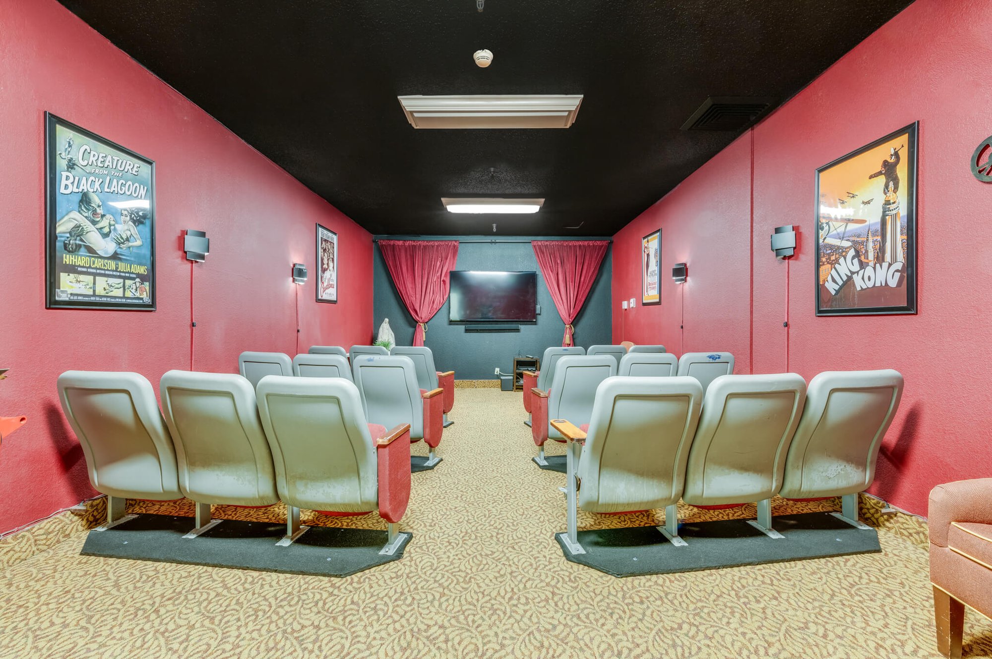 Cozy movie theater with red walls and seating.