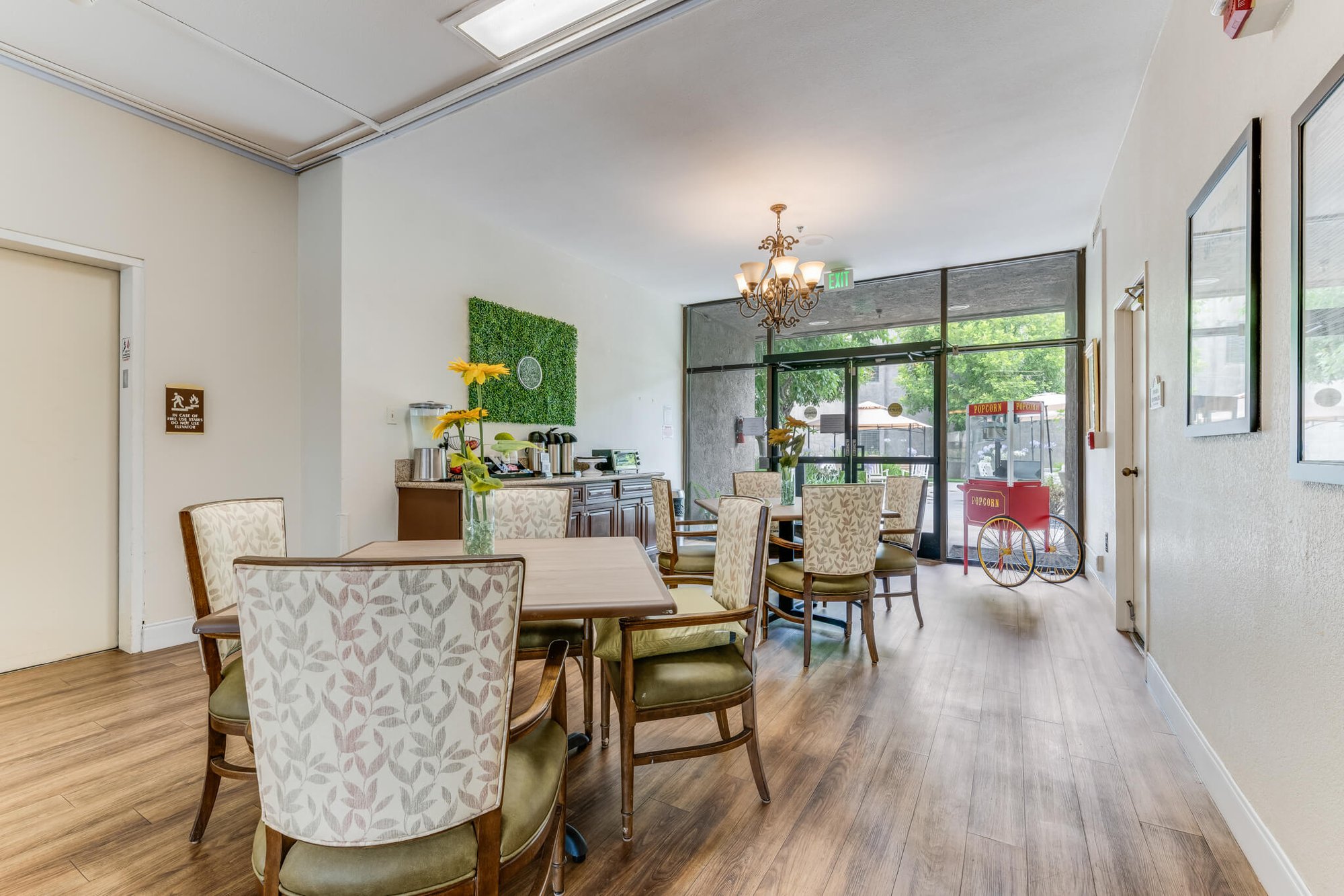 Bright common area with tables and plants.