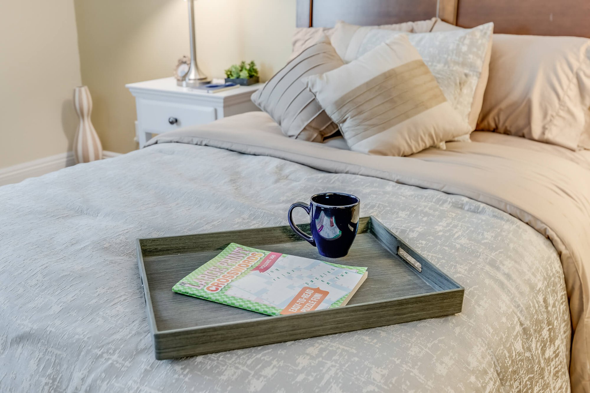 Cozy bedroom with a tray, book, and mug.